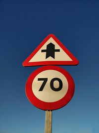 Low angle view of road sign against clear blue sky