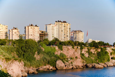 Buildings by sea against clear sky