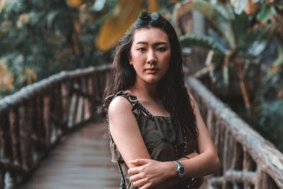 Portrait of young woman standing on footbridge