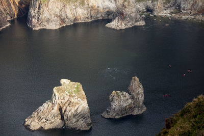 High angle view of kayakers dolphin watching amongst rocks in sea at slieve league, donegal. 