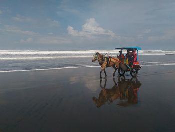 Man riding motorcycle on beach against sky