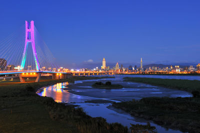 Illuminated bridge over river at night