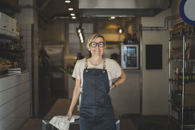 Portrait of smiling female owner with hand on hip in store