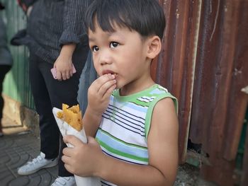 Cute boy eating fast food outdoors