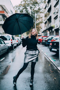 Full length of woman standing on wet street in city