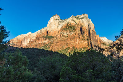 Low angle view of rocky mountain against blue sky