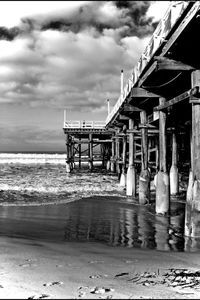 Pier on sea against cloudy sky