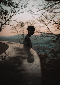 Side view of man by retaining wall against sky during sunset