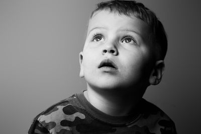 Portrait of boy looking away against gray background