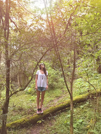 Full length of young woman standing in forest