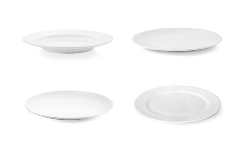 Close-up of empty plates against white background