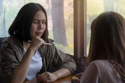 Portrait of young woman looking away while sitting at home