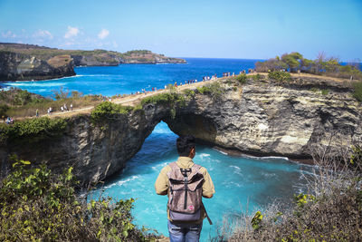 Rear view of man standing by sea against sky