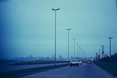 Cars on road against sky in city