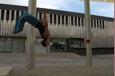 Full length of man performing stunt on footpath against building