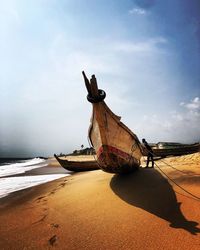 Fishing boat on beach against sky