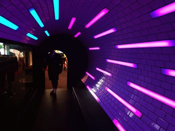 Full length of silhouette woman standing in illuminated tunnel