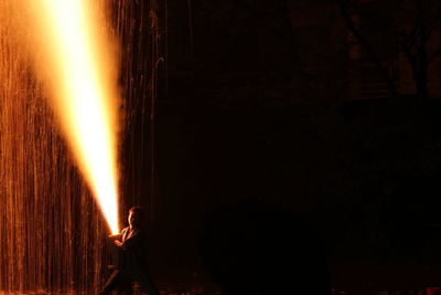 Silhouette people against illuminated fire at night