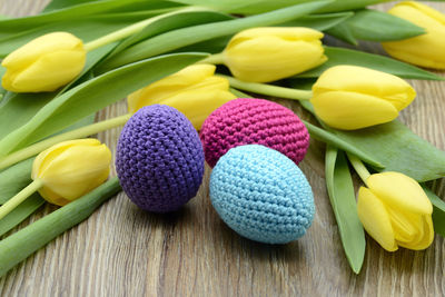 Close-up of multi colored woolen eggs and tulips on table