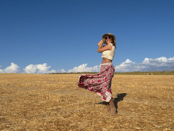 Full length of woman standing on field against clear blue sky