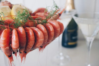 Close-up of cooked prawns with wine glasses on table