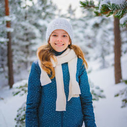 The joy of the winter. portrait of smiling young girl standing against trees during winter.