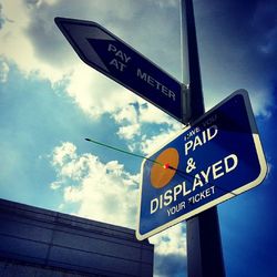 Low angle view of road sign against blue sky