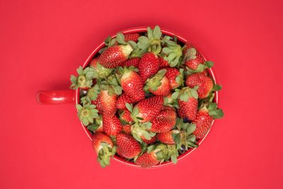 High angle view of strawberries in bowl against red background