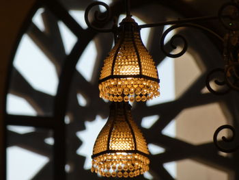 Low angle view of illuminated pendant lights hanging on ceiling in building