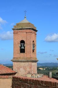 Bell tower in city against blue sky