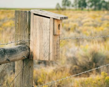 Close-up of wooden post on field against sky