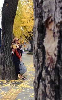 Woman sitting on tree trunk during autumn