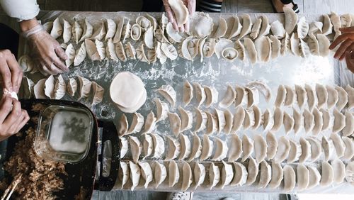 Cropped hands of people making dumplings in kitchen