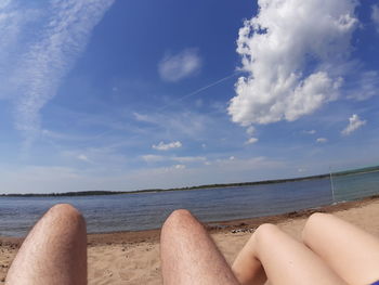 Low section of person on beach against sky