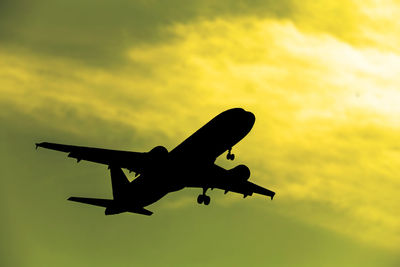 Low angle view of silhouette airplane against sky during sunset