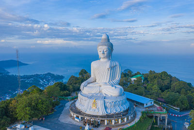 Statue against temple and building against sky