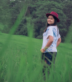 Portrait of smiling woman standing on grassy field 