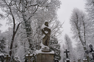 Low angle view of statue against bare trees during winter