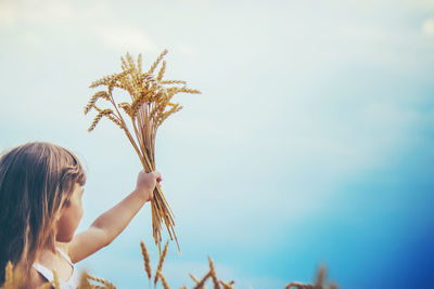 Side view of woman with arms raised against sky