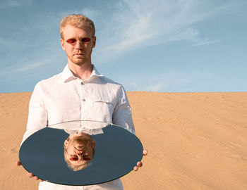 Portrait of young man standing against sky