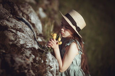 Midsection of girl smelling flower outdoors