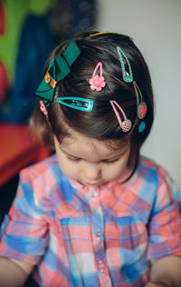 Close-up of cute girl wearing various hair clip while sitting at home