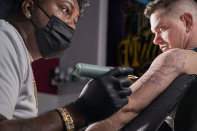 Tattoo artist making tattoo on arm