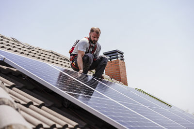 Technician installing solar panels on rooftop