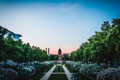 Ornamental garden outside historic building against sky during sunset