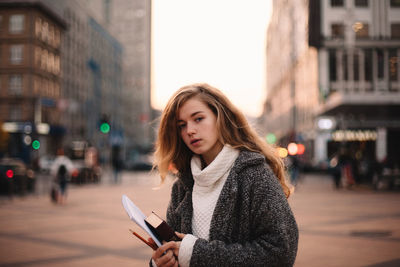 Portrait of young woman using phone on street in city