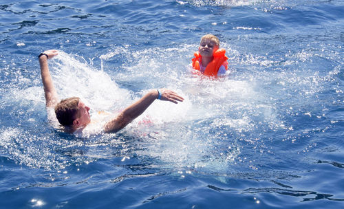 Father and son enjoying in sea during sunny day