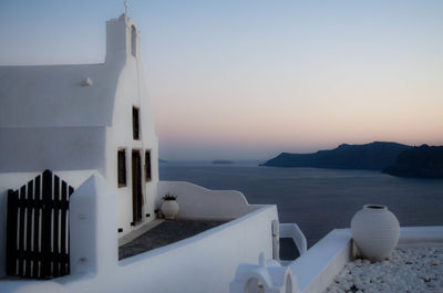 House and sea against sky during sunset