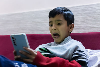 Young kid facial expression while watching mobile and playing online game at home at night