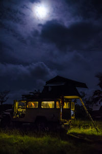 Offroad camping vehicle on field against sky at night